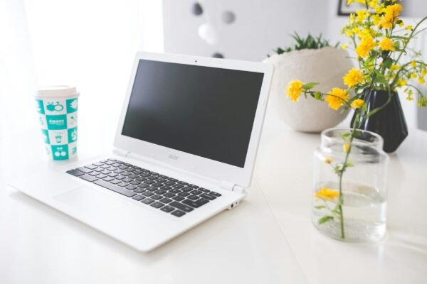 Bright workspace featuring Acer laptop, coffee cup, and fresh yellow flowers in a minimalist setting.
